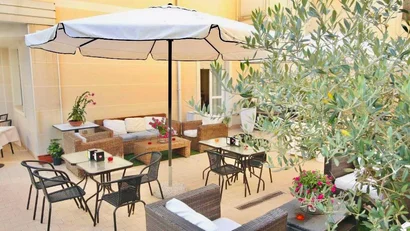 SM Hotels: ti meriti il mare tutto l’anno Zona pranzo all'aperto con ombrellone, sedie e tavoli in un cortile