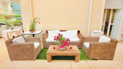 SM Hotels: ti meriti il mare tutto l’anno Salotto esterno con mobili in rattan e fiori rosa su tavolo