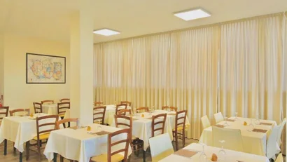 SM Hotels: ti meriti il mare tutto l’anno Sala ristorante con tavoli apparecchiati e sedie in legno e plastica