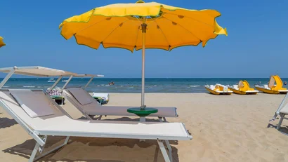 SM Hotels: ti meriti il mare tutto l’anno Ombrellone giallo e lettini sulla spiaggia con vista mare e pedalò