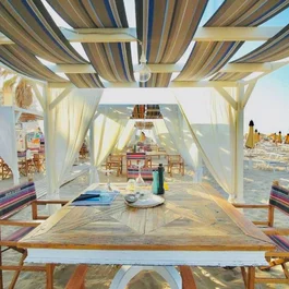 SM Hotels: ti meriti il mare tutto l’anno Area pranzo coperta sulla spiaggia con sedie e tavoli di legno