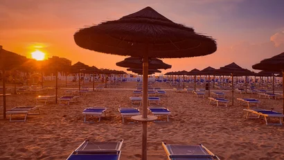 SM Hotels: ti meriti il mare tutto l’anno Ombrelloni di paglia e sdraio su spiaggia al tramonto